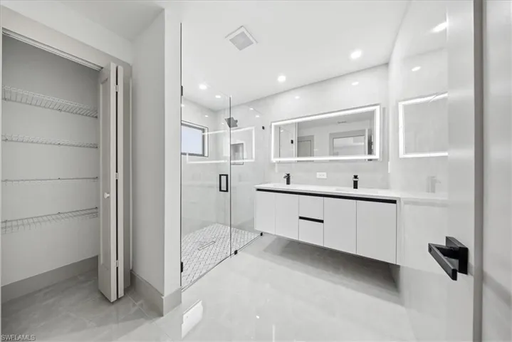 Full bathroom featuring a marble finish shower, double vanity, a spacious closet, and recessed lighting