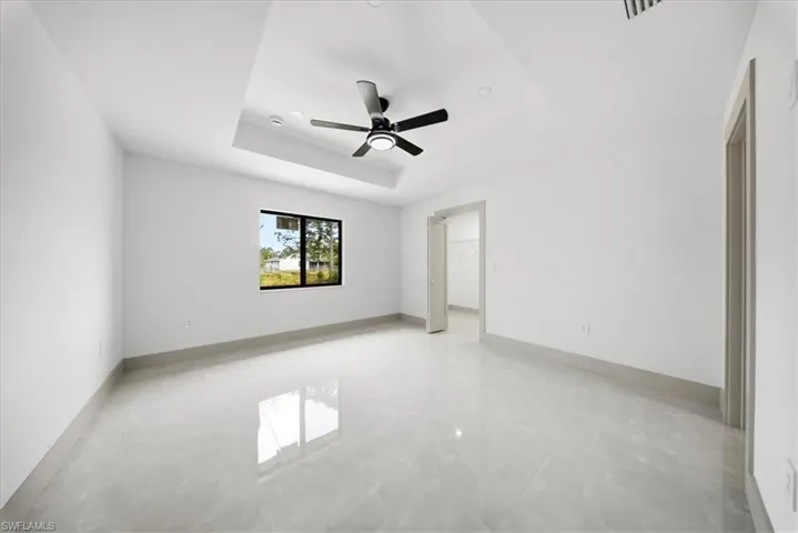 Empty room featuring a tray ceiling and ceiling fan