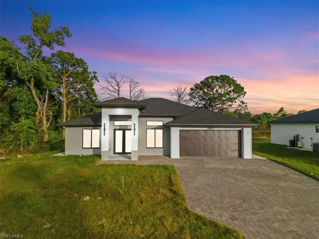 Prairie-style home with a yard, a garage, driveway, and stucco siding
