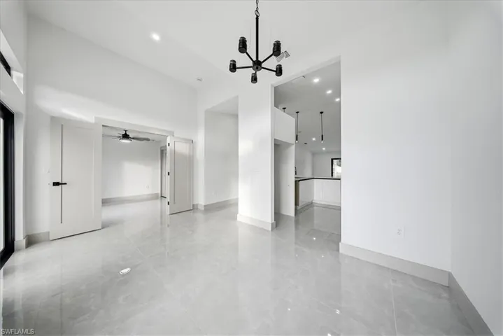 Unfurnished living room with a high ceiling, a chandelier, and a ceiling fan