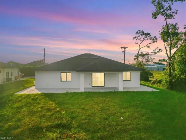 Back of house at dusk featuring a patio area, a yard, and stucco siding