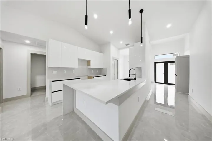 Kitchen with light stone counters, white cabinets, modern cabinets, lofted ceiling, and a breakfast bar area