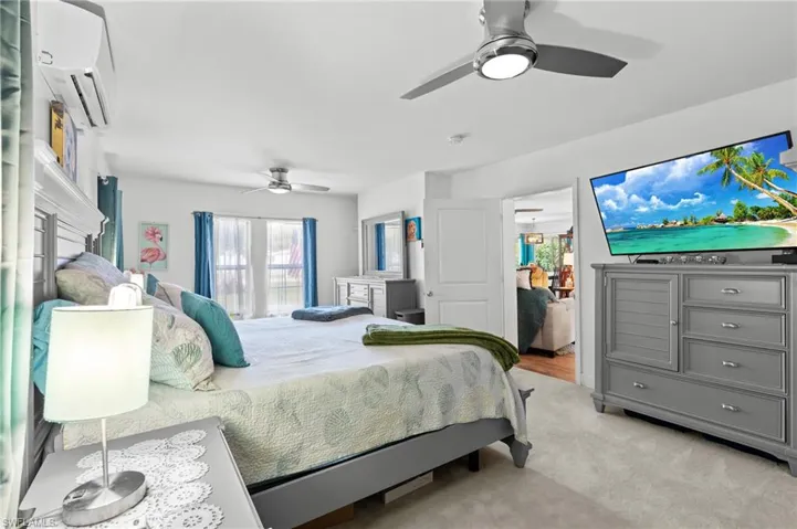 Bedroom featuring light carpet, a wall mounted AC, and ceiling fan