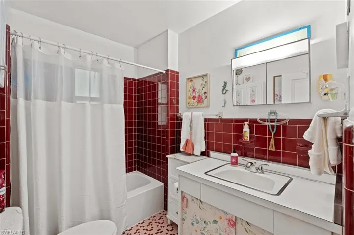 Bathroom featuring sink, shower / bath combination with curtain, and decorative backsplash
