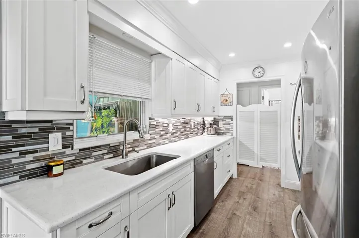 Kitchen with white cabinetry, appliances with stainless steel finishes, sink, and light wood-type flooring