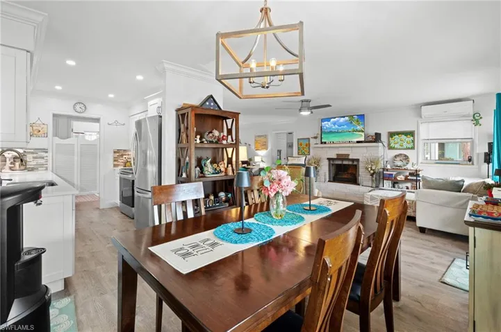 Dining area with light hardwood / wood-style floors, a fireplace, a wall mounted AC, and sink