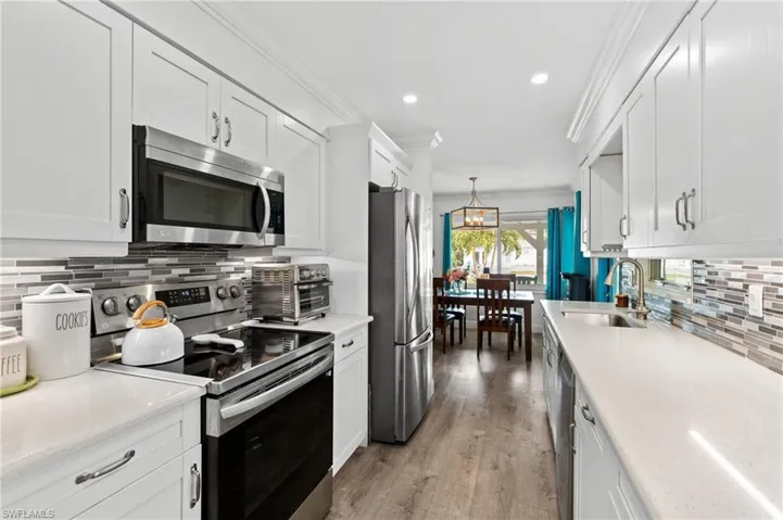 Kitchen featuring sink, hanging light fixtures, white cabinets, and appliances with stainless steel finishes