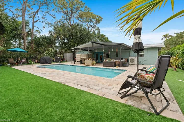View of pool with area for grilling, a lawn, outdoor lounge area, and a patio