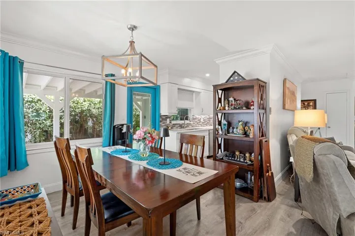 Dining room featuring an inviting chandelier, ornamental molding, sink, and light wood-type flooring
