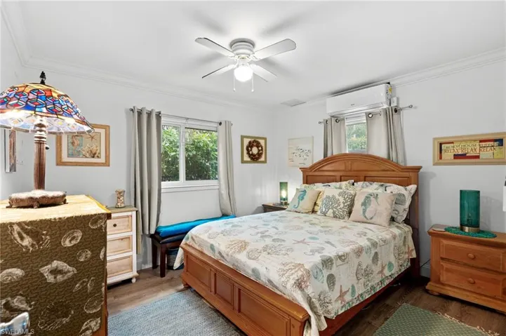 Bedroom with dark hardwood / wood-style flooring, crown molding, an AC wall unit, and ceiling fan