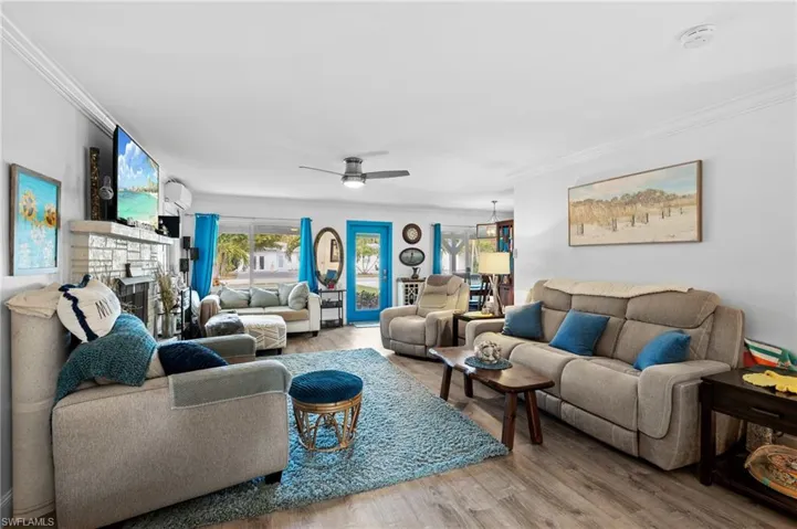 Living room with crown molding, hardwood / wood-style floors, ceiling fan, and a fireplace