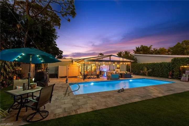 Pool at dusk with a grill, an outdoor hangout area, and a patio area
