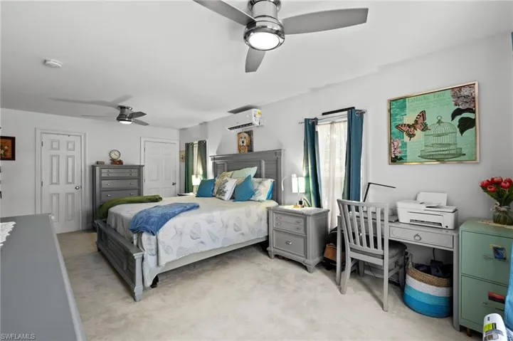 Carpeted bedroom with ceiling fan and an AC wall unit
