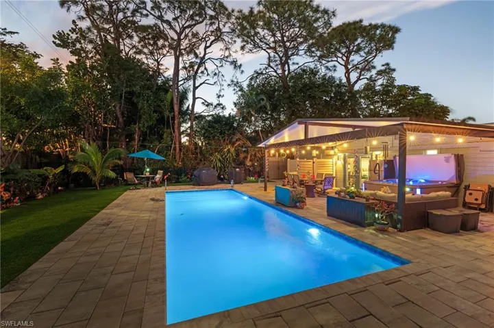 Pool at dusk with an outdoor structure, outdoor lounge area, and a patio area
