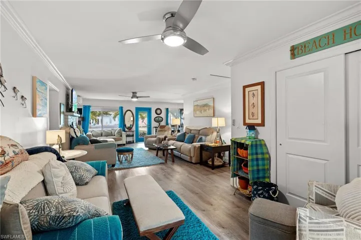 Living room with ornamental molding, ceiling fan, and light wood-type flooring