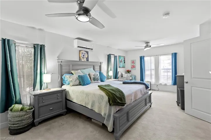 Carpeted bedroom featuring ceiling fan and a wall unit AC