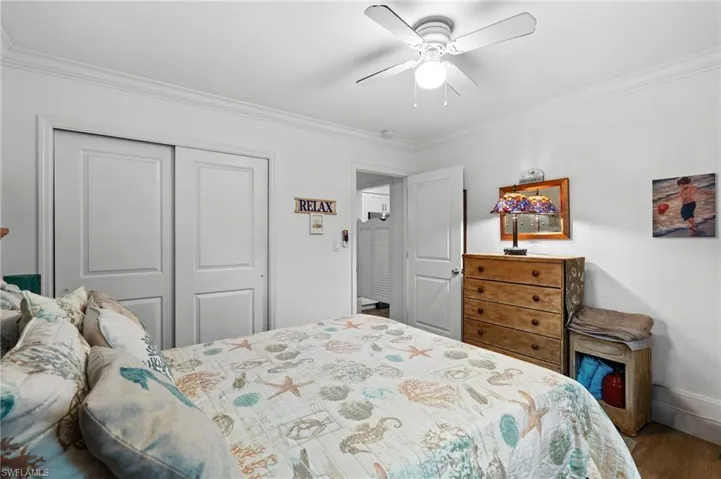 Bedroom with hardwood / wood-style floors, ornamental molding, a closet, and ceiling fan