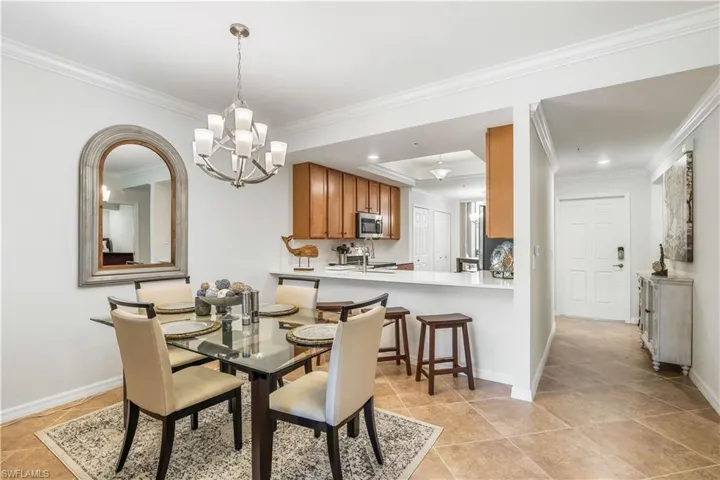 Tiled dining area featuring ornamental molding, sink, and a chandelier