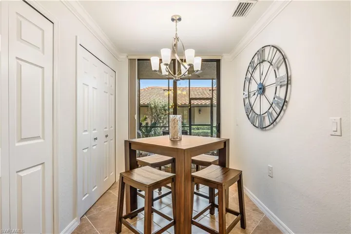 Dining area with tile patterned flooring, crown molding, and an inviting chandelier