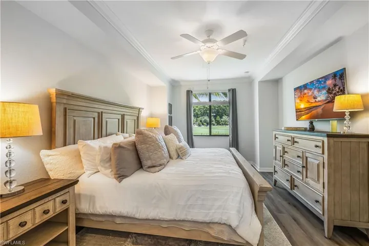 Bedroom featuring dark wood-type flooring, ornamental molding, and ceiling fan