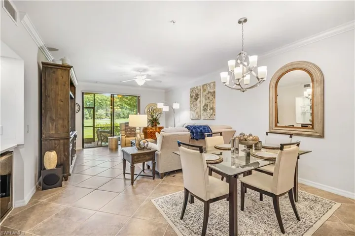Dining area featuring light tile patterned flooring, ceiling fan with notable chandelier, and ornamental molding