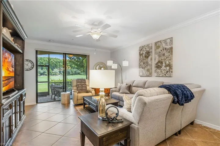 Living room with light tile patterned flooring, ceiling fan, and crown molding
