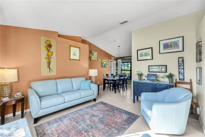 Living area with lofted ceiling, light tile patterned flooring, ceiling fan, and visible vents