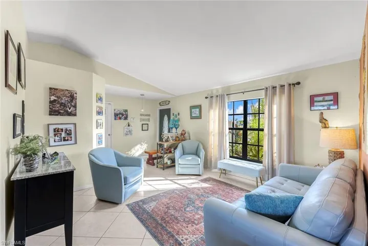 Living area featuring lofted ceiling, baseboards, visible vents, and light tile patterned flooring