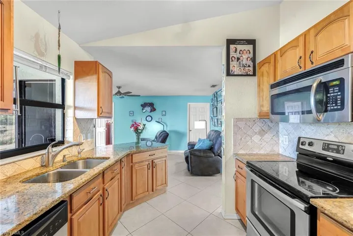 Living area featuring light tile patterned floors, baseboards, and vaulted ceiling