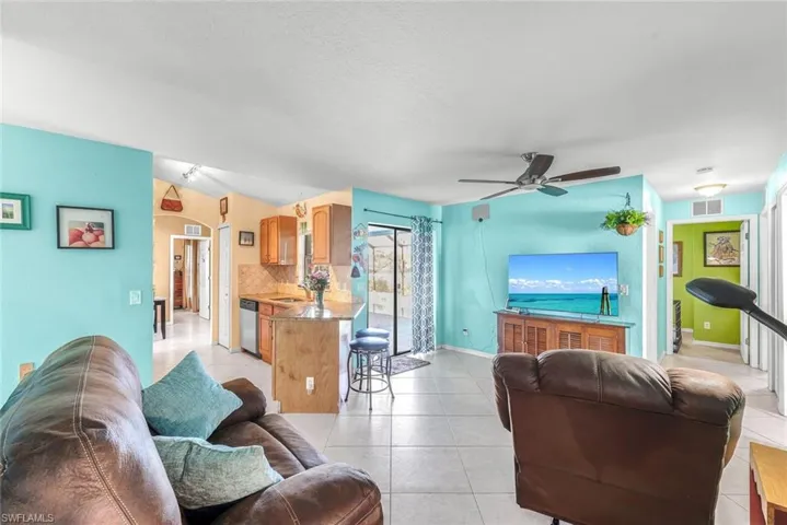 Living room with visible vents, ceiling fan, baseboards, and light tile patterned floors