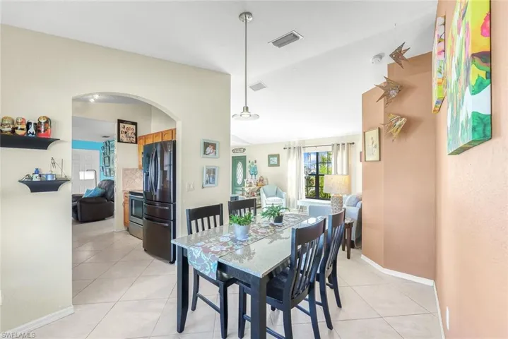 Dining room with visible vents, vaulted ceiling, baseboards, and light tile patterned floors