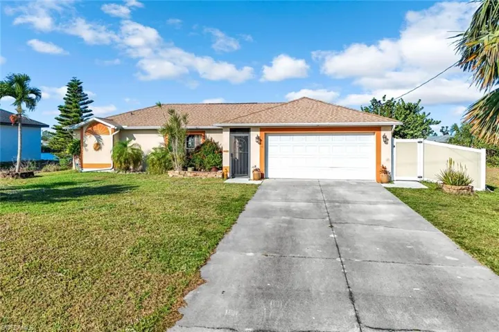 Ranch-style house featuring driveway, a front lawn, an attached garage, and stucco siding