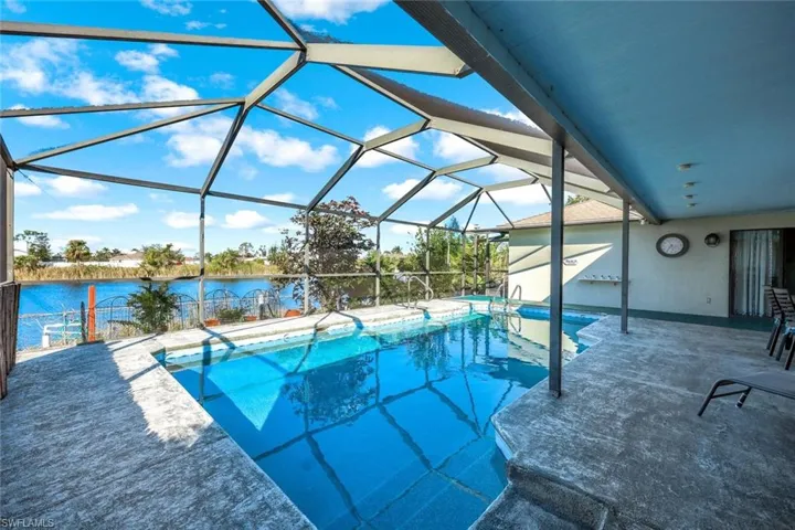 Outdoor pool with a patio area, glass enclosure, a water view, and outdoor dining space