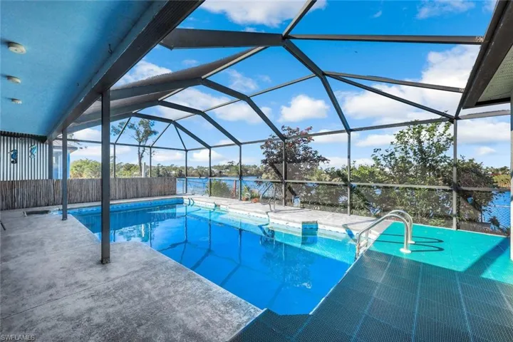 Pool with glass enclosure, fence, and a patio