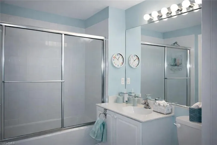 Guest Bathroom featuring vanity and shower / bath combination with glass door