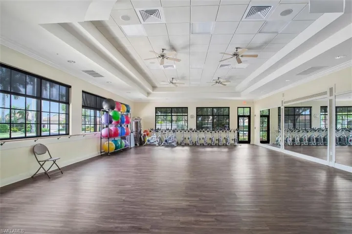 Workout room with a tray ceiling, ornamental molding, dark hardwood / wood-style floors, and ceiling fan