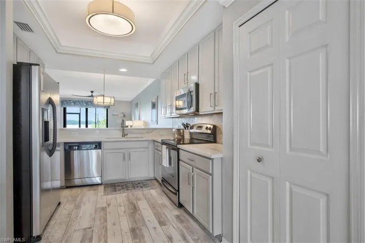 Kitchen featuring light hardwood / wood-style flooring, appliances with stainless steel finishes, decorative light fixtures, sink, and ornamental molding