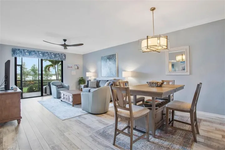 Dining room with ceiling fan with notable chandelier, crown molding, and hardwood / wood-style flooring