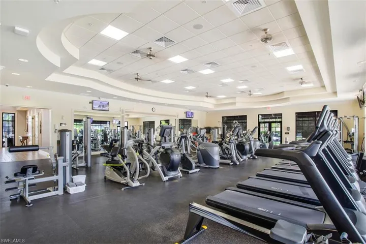 Gym with ceiling fan, a raised ceiling, and a drop ceiling