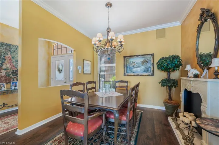 Dining room with crown molding, dark hardwood / wood-style flooring, and a notable chandelier