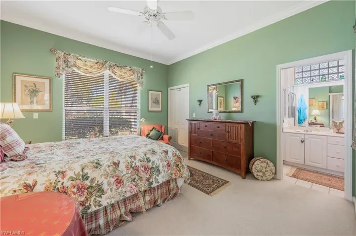 Bedroom with crown molding, ensuite bath, ceiling fan, carpet floors, and a closet