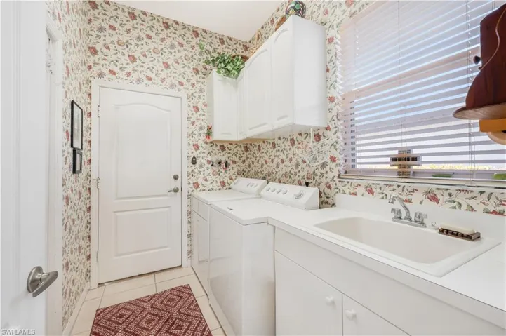 Laundry area featuring cabinets, sink, light tile patterned floors, and washing machine and clothes dryer