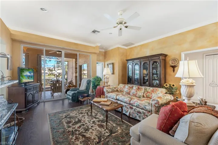 Living room featuring ceiling fan, ornamental molding, and dark hardwood / wood-style flooring