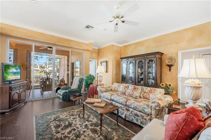 Living room with ornamental molding, dark hardwood / wood-style floors, and ceiling fan