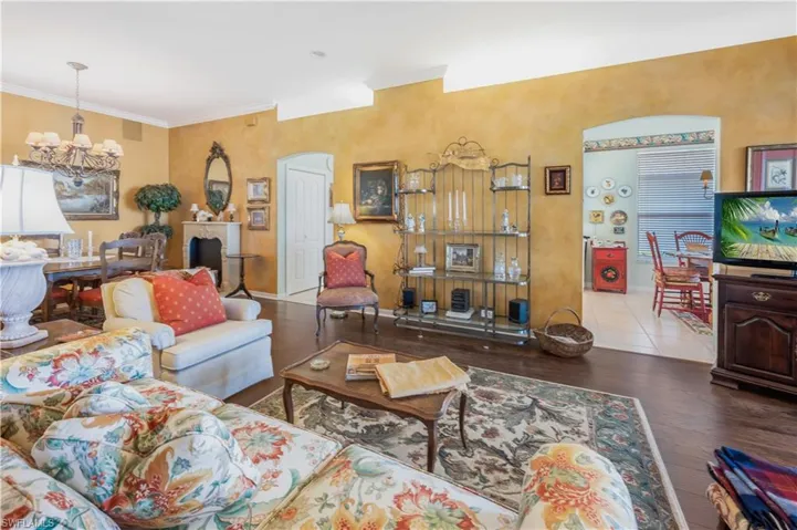 Living room with an inviting chandelier, ornamental molding, and hardwood / wood-style floors