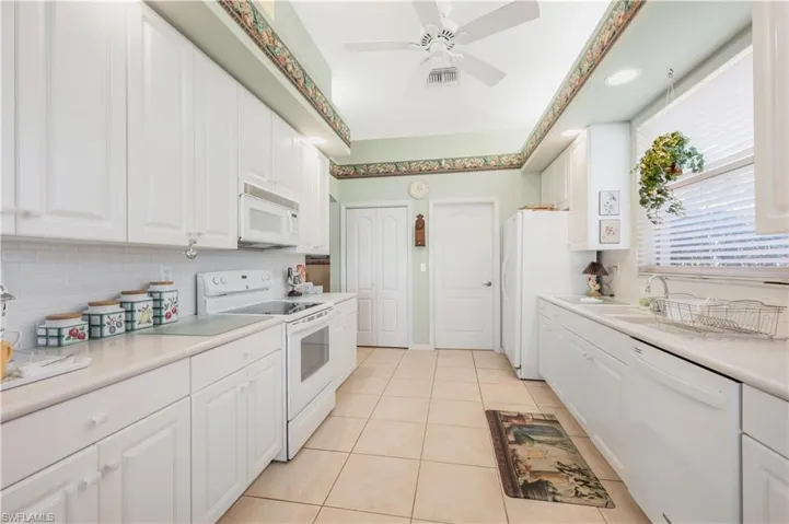 Kitchen featuring tasteful backsplash, white cabinetry, light tile patterned floors, ceiling fan, and white appliances