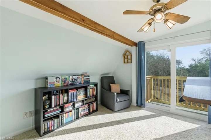Living area featuring lofted ceiling with beams, carpet floors, and a ceiling fan