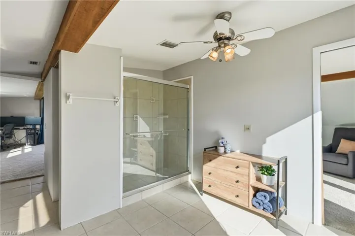 Bathroom featuring a stall shower, light tile patterned floors, and ceiling fan