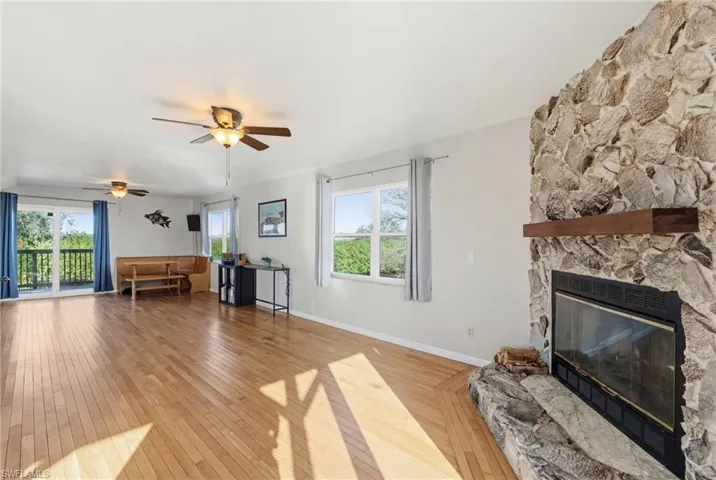 Living area with light wood-type flooring, a fireplace, and a ceiling fan