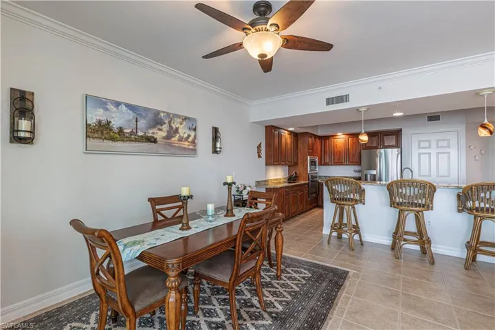 Dining space featuring ceiling fan, ornamental molding, light tile patterned flooring, and baseboards
